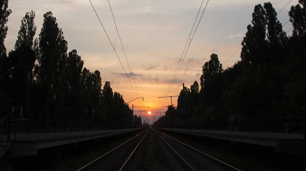Spoorlijn bij zonsondergang, een platform van de spoorweg met ozhidayuschimi passagiers — Stockfoto