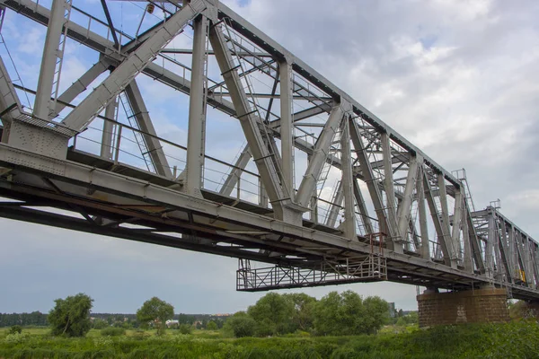 Puente ferroviario hecho de estructuras de hierro, sobre un fondo nublado del cielo — Foto de Stock