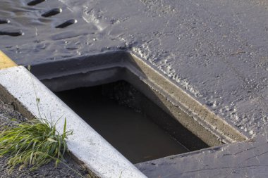 Çukur asfalt yakınındaki sokağın ortasında kanalizasyon kapağı içinde