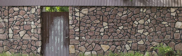 Odběr vzorků z přírodní kamenná zídka s stará dřevěná vrata — Stock fotografie