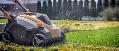 Bahçede çim havalandırma. Yeşil çimenlerin üzerinde sarı aerator yakın çekim