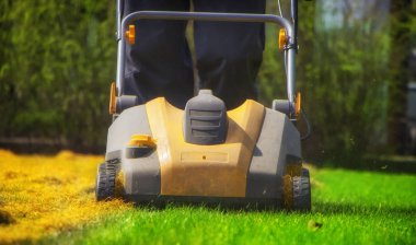 Bahçede çim havalandırma. Yeşil çimenlerin üzerinde sarı aerator yakın çekim