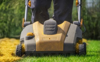Bahçede çim havalandırma. Yeşil çimenlerin üzerinde sarı aerator yakın çekim