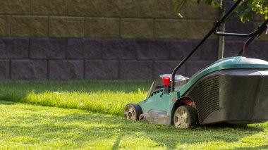 Çim biçme makinesi arka bahçede yeşil çim biçiyor..