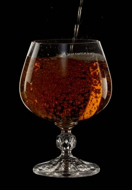 Konyak bir cam içine dökülür, bir sprey siyah bir zemin üzerine bir içki ile yakın çekim