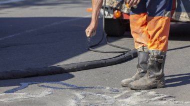 İşçiler yol onarım, daha fazla yol yüzeyi imha önlemek için bitüm ile küçük çatlaklar dökün. Yakın çekim