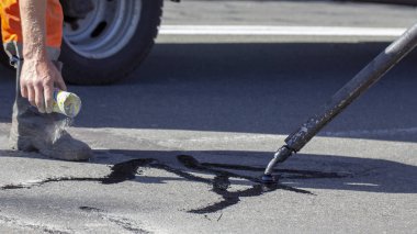 İşçiler yol onarım, daha fazla yol yüzeyi imha önlemek için bitüm ile küçük çatlaklar dökün. Yakın çekim