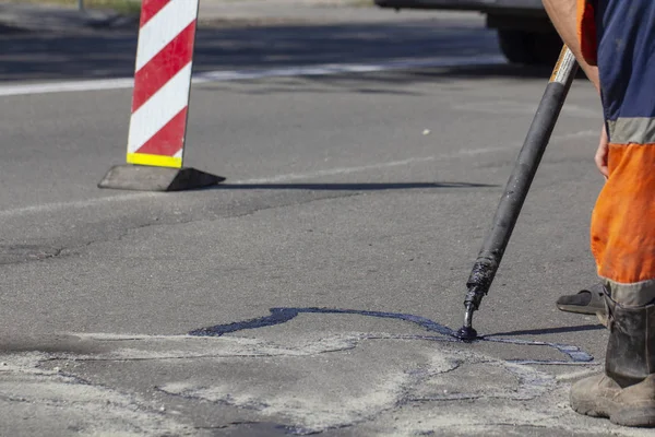 İşçiler yol onarım, daha fazla yol yüzeyi imha önlemek için bitüm ile küçük çatlaklar dökün. Yakın çekim