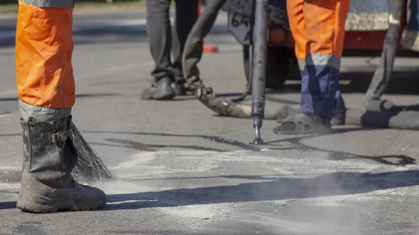 İşçiler yol onarım, daha fazla yol yüzeyi imha önlemek için bitüm ile küçük çatlaklar dökün. Yakın çekim