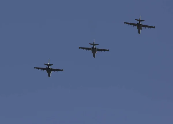 Several military fighters are flying in a formation against the blue sky.