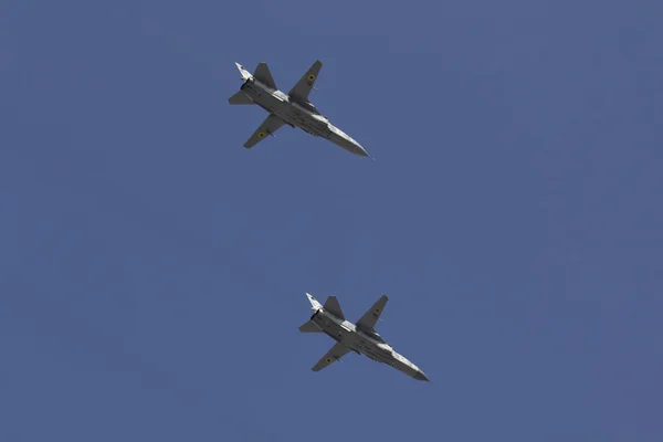 Several military fighters are flying in a formation against the blue sky.