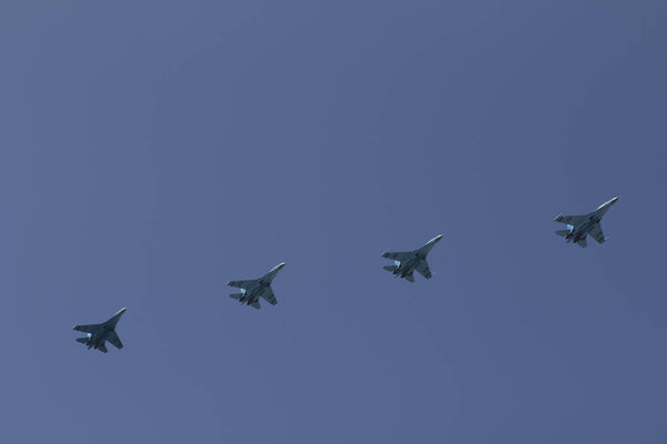Several military fighters are flying in a formation against the blue sky.