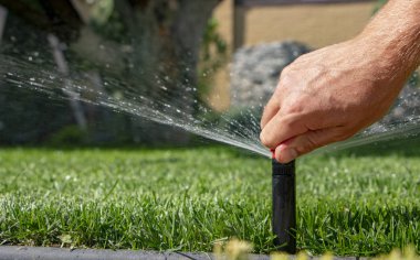 Otomatik fıskiye sistemi yeşil çimlerin arka planında çimenleri suluyor, yakın plan