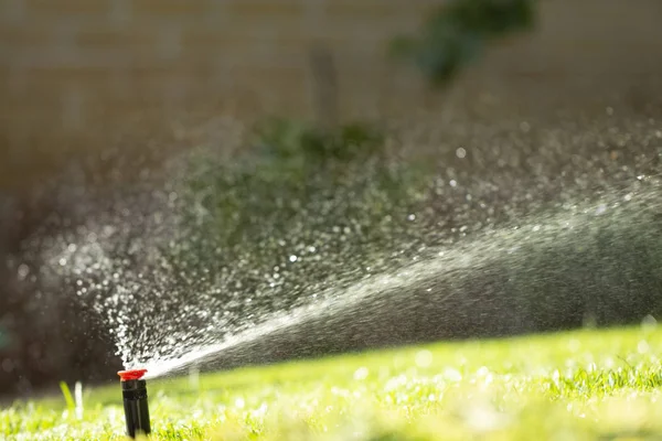 緑の草を背景に芝生に散水する自動散水システム クローズアップ — ストック写真