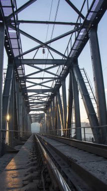 Sabah sisinde bir demiryolu köprüsü ya da güneş ışınlarının arka planda parladığı bir duman..