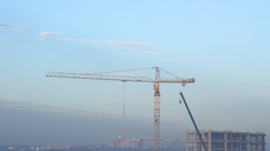 İnşaat alanında. İnşaat vinçleri ve yüksek katlı bina inşaat mavi gökyüzü altında.