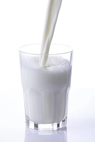 Наливая Стакан Молока Создавая Всплеск Белом Фоне Крупным Планом — стоковое фото