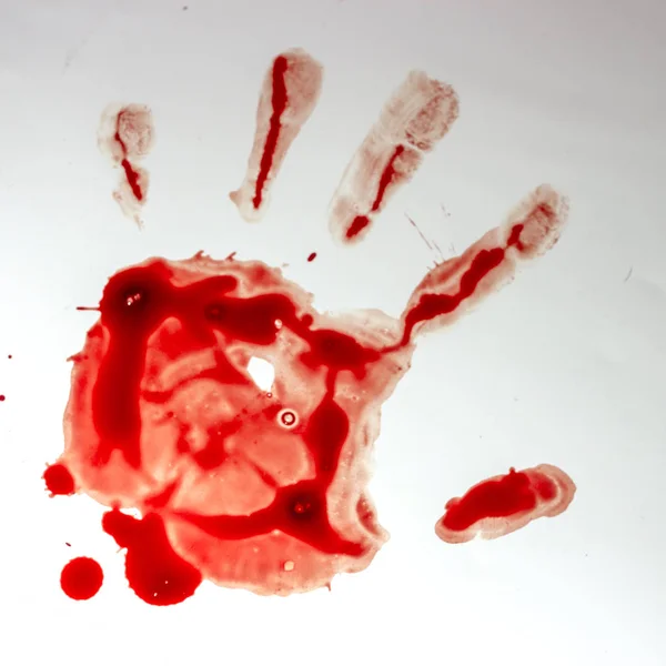 Red imprint of the bloody palm on a white background close up