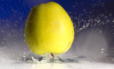 Yeşil elma ve renkli bir arka plan üzerinde su sıçramalarına kapat