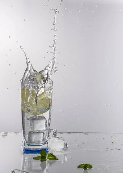 Sklenici limonády na světlém pozadí s šplouchání vody — Stock fotografie