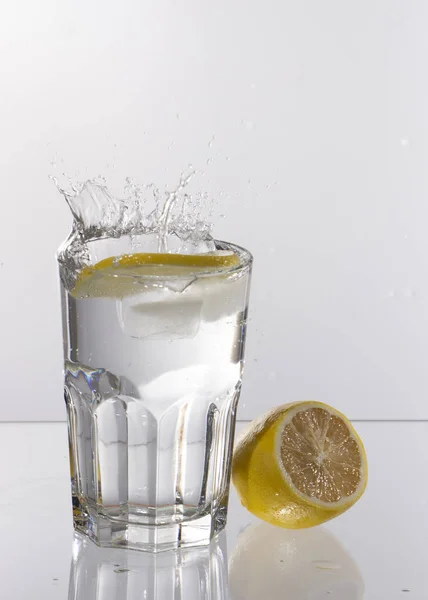 Sklenici limonády na světlém pozadí s šplouchání vody — Stock fotografie