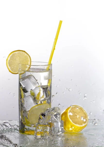 A glass of lemonade on a light background with splashing water — Stock Photo, Image