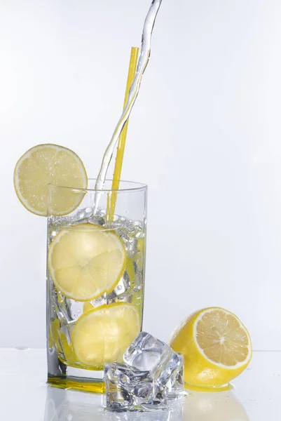 Un vaso de limonada sobre un fondo claro con agua salpicada — Foto de Stock