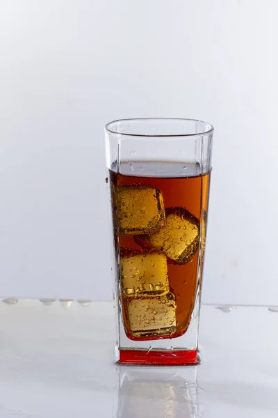 Cold refreshing soft drink with ice on white background close up