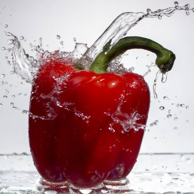 Tatlı biber damla su su beyaz zemin üzerine kırmızı biber sıçrama, yakın çekim
