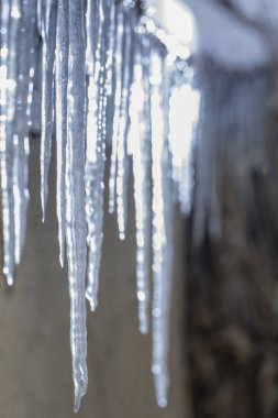 Buz sarkıtları eski, paslı, kırsal bir çatıda. Kil duvar yakın çekim