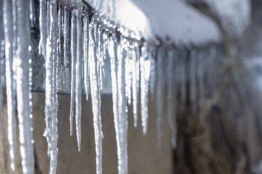 Buz sarkıtları eski, paslı, kırsal bir çatıda. Kil duvar yakın çekim