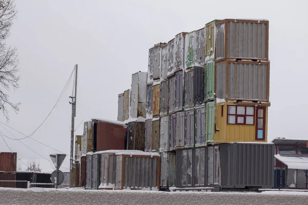 Four vertical rows of shipping containers that are different colors On the side of the road