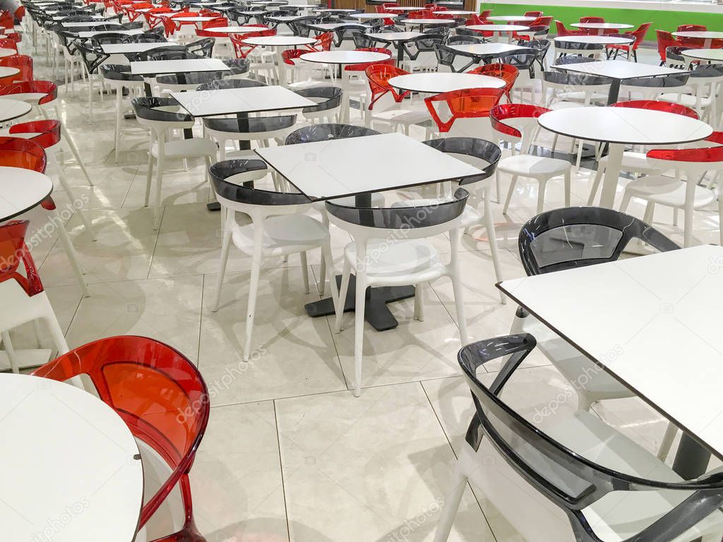 Many empty plastic tables in the open cafe.