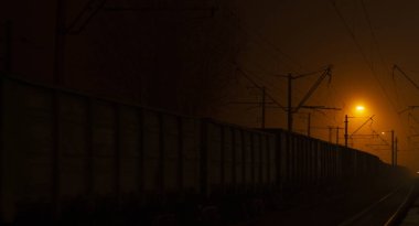 Tren Platformu geceleri geliyor. Parlak ışık ışınlarının karanlık dağıtmak. Arka plan