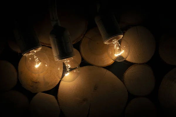 Dim light bulb on the background of a wooden log wall