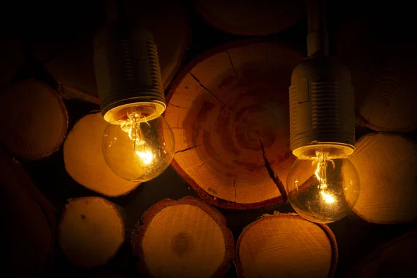 Dim light bulb on the background of a wooden log wall - Stock Image -  Everypixel