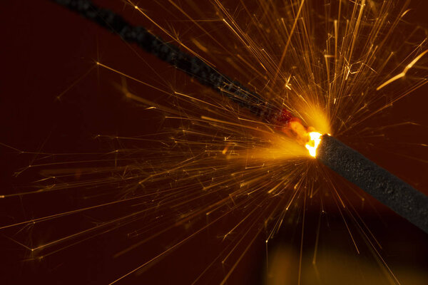 Flaming sparkler on red background close up