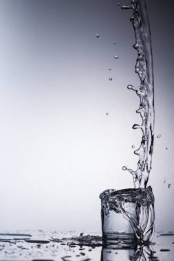 Saf içme su sıçramalarına açık yeşil arka planı üzerinde yuvarlak bir cam ile yakın çekim