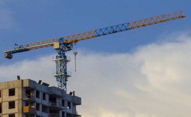 İnşaat alanında. İnşaat vinçleri ve yüksek katlı bina inşaat mavi gökyüzü altında.