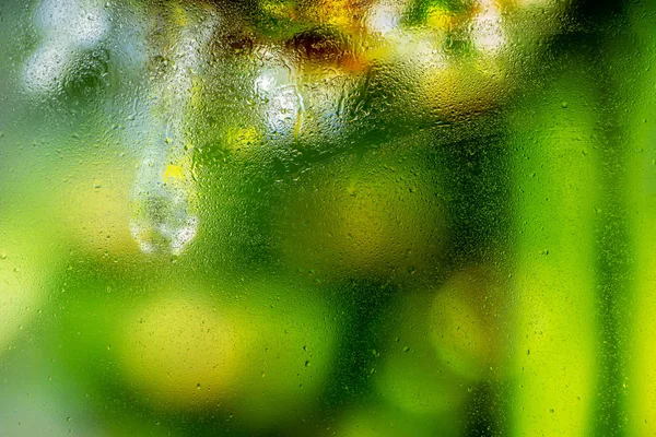 Water droplets on a window pane with beautiful defocused scenery outside. Background
