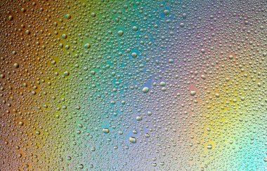 Gökkuşağının yansımasıyla camın üzerine su damlaları. Arka plan