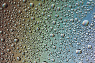 Gökkuşağının yansımasıyla camın üzerine su damlaları. Arka plan