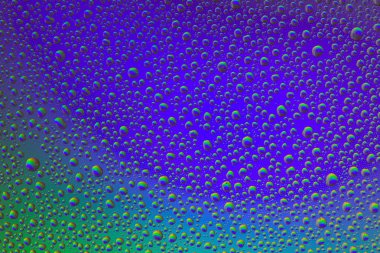 Gökkuşağının yansımasıyla camın üzerine su damlaları. Arka plan