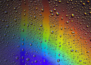 Gökkuşağının yansımasıyla camın üzerine su damlaları. Arka plan