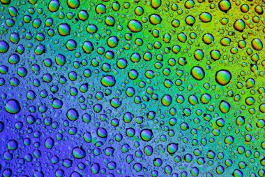 Gökkuşağının yansımasıyla camın üzerine su damlaları. Arka plan