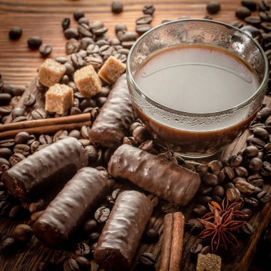 Eski ahşap arka planda kavrulmuş kahve çekirdekleri ile kahve fincanı yakın çekim.