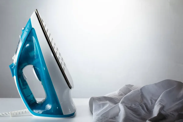Blue iron and shirt on ironing board iron board clothes ironing shirt household appliance electric concept