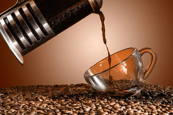 Pouring coffee into cup with splashing on brown background. close up