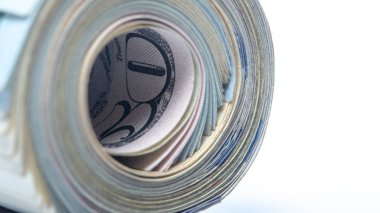 100 dolarlık banknotlar tüpe bükülmüş ve elastik bir bantla bağlanmış. beyaz arka plan. Yakın çekim