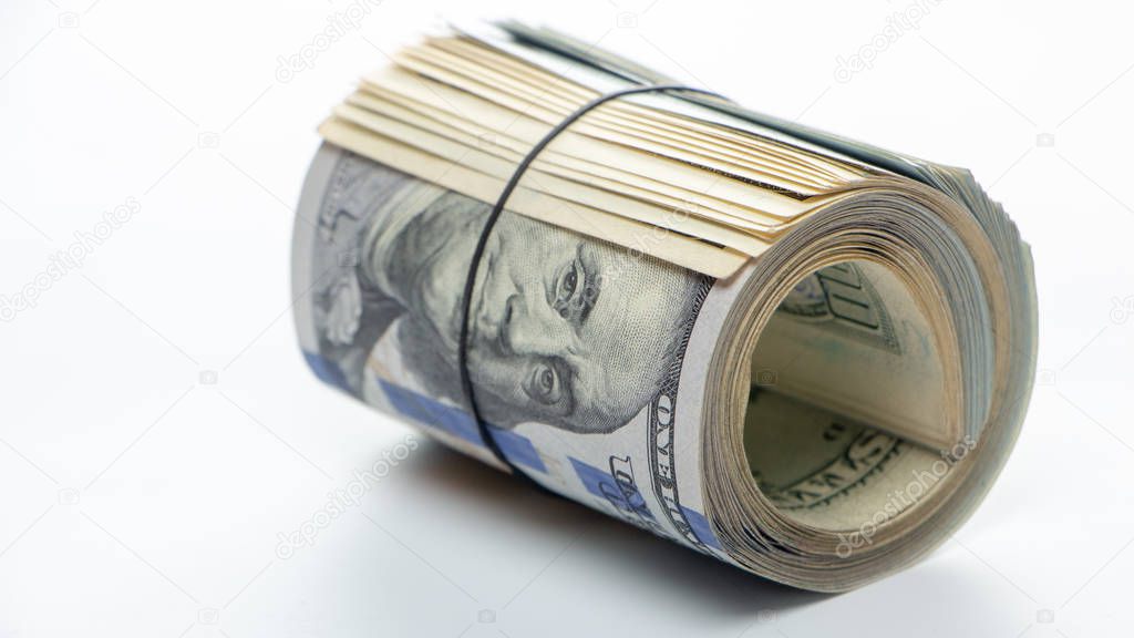 100 dollar bills twisted into tube and tied with an elastic band. white background. Close up